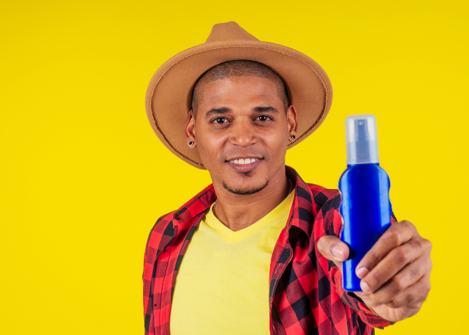 man wearing a hat and using sunblock to protect his scalp